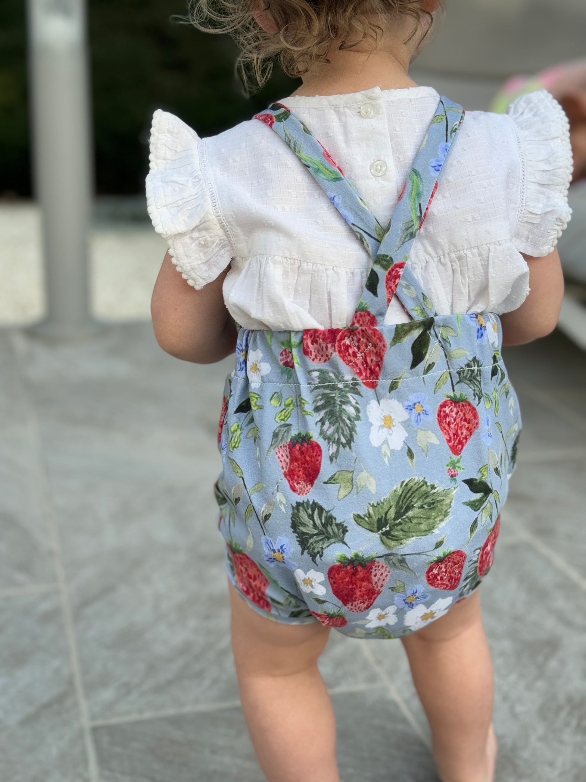 a toddler wearing Strawberry Whimsy Bubble romper standing on tiled floor